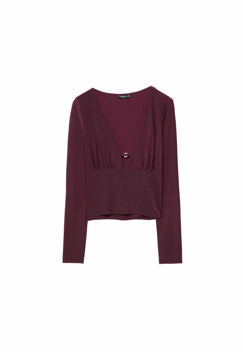 Top lungo bordeaux a maniche lunghe con scollatura a V profonda, dettagli arricciati in vita e orlo corto. Realizzato in un morbido tessuto leggero.
