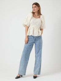 White textured blouse with puff sleeves and a square neckline, paired with light blue wide-leg jeans and black square-toed shoes.