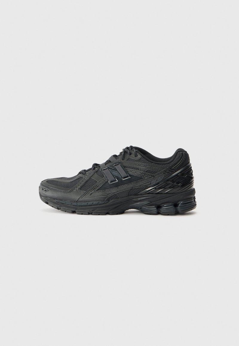 Chaussure de sport New Balance noire avec semelle rembourrée, dessus en mesh et cuir, et lacets, vue de côté droit sur un fond gris.