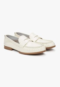 White leather loafers with a bow accent, featuring a moccasin-style stitching and flat tan rubber soles. Smooth texture and rounded shape.