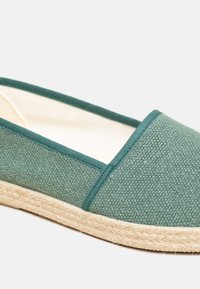 Green canvas espadrille with a textured upper and contrasting stitched trim, featuring a natural jute rope sole.