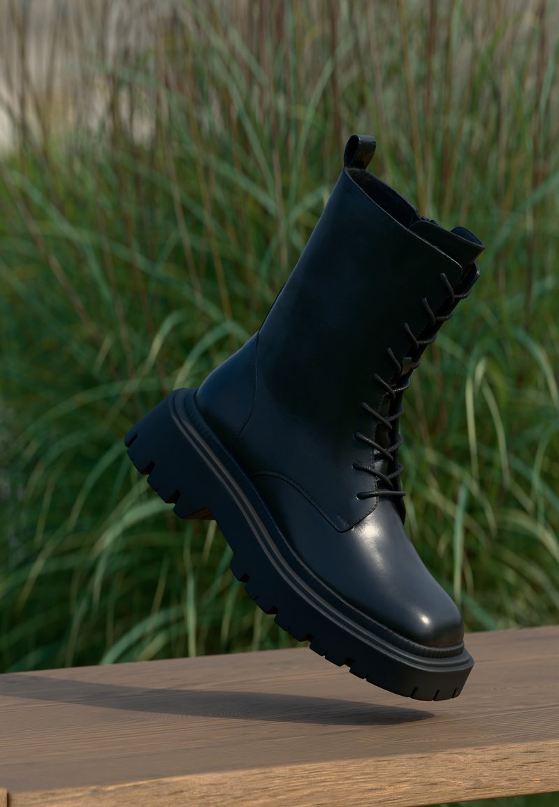 Black leather ankle boot with a rounded toe, lace-up front, and chunky rubber sole. Smooth finish with textured accents and pull tab.