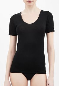 T-shirt nero a maniche corte realizzato in tessuto morbido, con scollatura ampia e design aderente. Texture liscia e cuciture minime.
