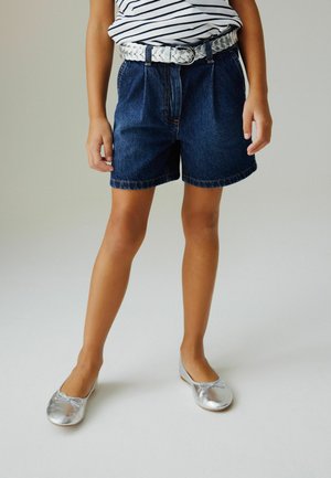 Pantaloni scurți din denim cu croială lejeră, culoare albastru închis și tivuri întoarse. Purtați împreună cu o curea argintie împletită și balerini argintii strălucitori.