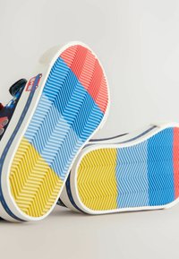Färgglada sneakersulor med ett strukturerat, zigzag-mönster i blå, röd och gul sektion samt en vit gummiram.