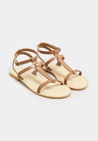 Braune Leder-Sandalen mit mehreren Riemen, offenes Zehendesign, verstellbare Knöchelverschlüsse und flache Sohle in beige.