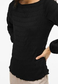Czarna teksturowana bluzka z długim rękawem, z okrągłym dekoltem, marszczonymi bufkami na rękawach i falowanym dołem, wykonana z lekkiego materiału.