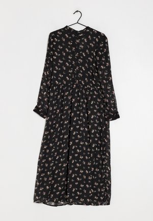 Czarna sukienka midi z długim rękawem, z małym różowo-białym kwiatowym wzorem, z przodu zapinana na guziki, zawieszona na czarnym wieszaku na białym tle.