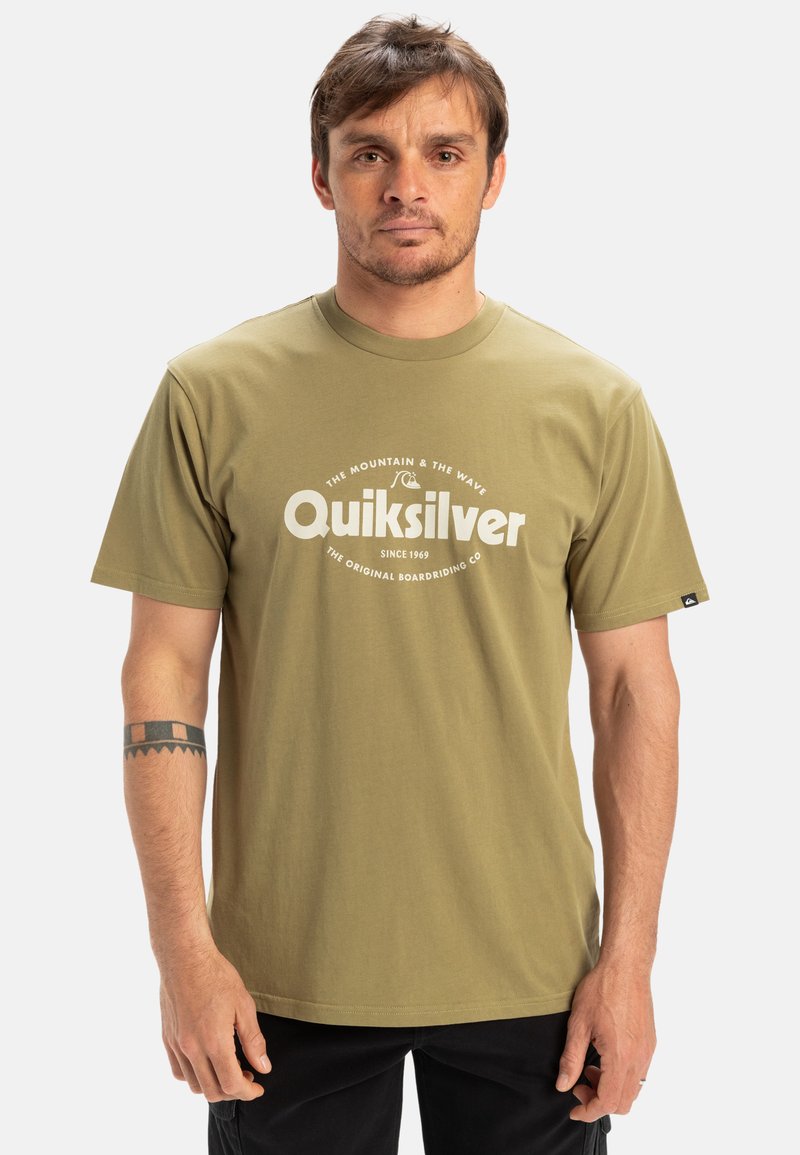 Oliven grøn T-shirt med korte ærmer lavet af bomuld, der har en rund halsudskæring og et stort hvidt trykt logo på fronten.