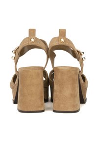 Sandali alti in suede color sabbia con ampi tacchi a blocco, schiena aperta e borchie decorative in oro sugli strap, caratterizzati da una texture liscia.