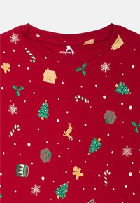 Camiseta de algodón roja con diseños festivos: árboles de Navidad, galletas de jengibre, caramelos y copos de nieve. Cuello redondo y mangas cortas.