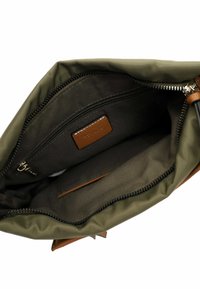 Olive green nylon bag interior features a tonal fabric lining, a zippered pocket, a brown leather accent, and a smooth zipper closure.