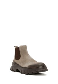 Bottines Chelsea en daim marron avec pan incliné élastique, semelle en caoutchouc épaisse, bout rond et détail de capuchon de bout contrastant.