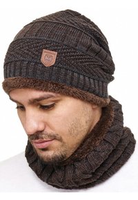 Brown knitted beanie with textured patterns and a soft faux-fur lining; features a leather patch with a logo. Attached matching neck warmer.