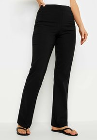 Zwarte, rekbare broek met een gladde textuur, voorzien van een brede tailleband en een uitlopende beenontwerp. Versterkt met platte naden en zonder zichtbare zakken.