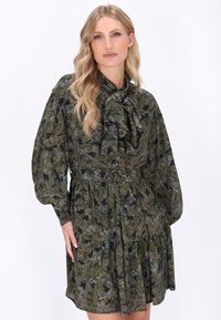 Sötétzöld és fekete virágmintás ruha, hosszú puff ujjal, megkötős dekoltázzsal és fodros aljjal. Könnyű anyagból készült.