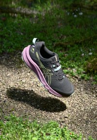 Baskets de sport noires avec une tige en mesh respirant, accents rose et lavande, dotées d'éléments réfléchissants et d'une semelle amortissante.