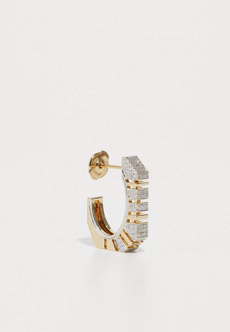 Cercei in forma de cerc de culoare aurie, cu segmente alternative de pietre artificiale clare și un finisaj metalic neted. Au un sistem de prindere sigur și un design geometric.