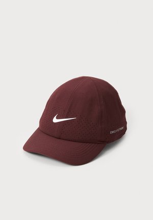 Casquette de sport bordeaux avec visière incurvée, logo Nike blanc et côtés perforés pour la ventilation. Marque Dri-FIT à l'arrière.