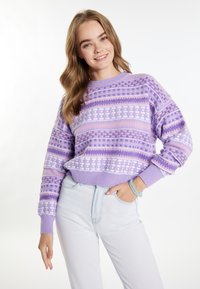 Cardigan viola con motivi a tonalità variabili, caratterizzato da disegni geometrici e un colletto rotondo a coste, abbinato a pantaloni di jeans chiari.