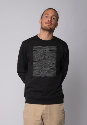 Black sweatshirt featuring a textured graphic of a hand made with horizontal lines. Crew neck and long sleeves with ribbed cuffs and hem.