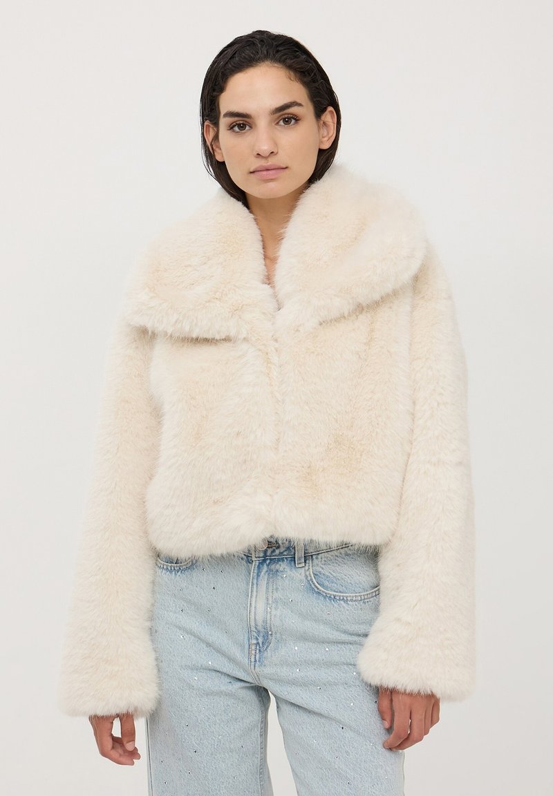 Giacca corta in finta pelliccia bianca con ampio colletto e maniche lunghe, caratterizzata da una superficie morbida e testurizzata e una chiusura a gancio.