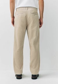 Beige corduroy trousers with a straight-leg design, featuring subtle vertical stripes, dual back pockets, and a waistband with belt loops.