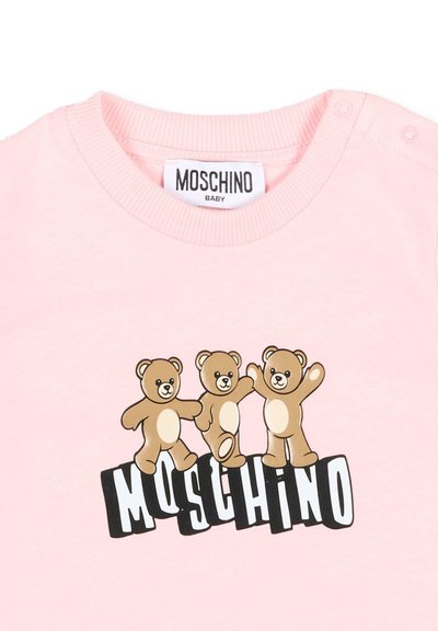Morbida maglietta rosa per bambini con tre orsetti danzanti sopra il testo stilizzato "MOSCHINO" in bianco e nero.