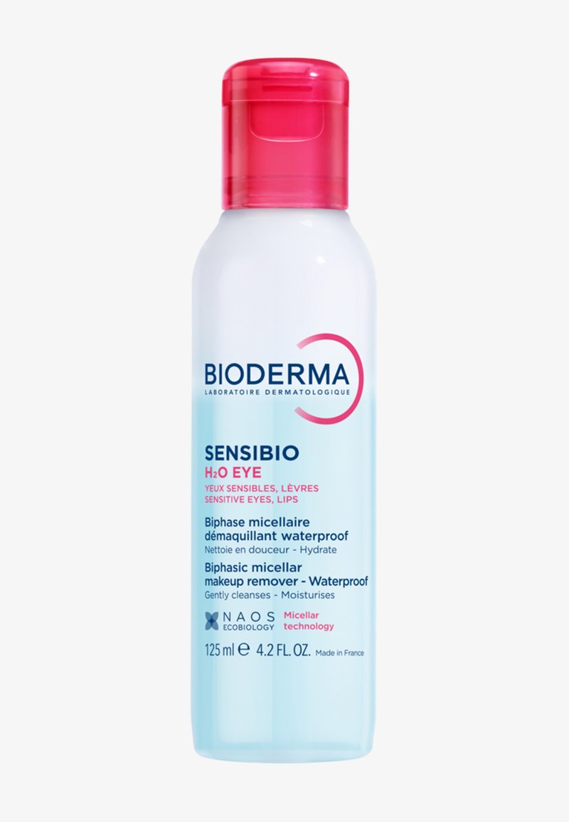 Bioderma Sensibio H2O struccante per occhi, in una bottiglia di plastica trasparente con un tappo a scatto rosso, presenta un liquido blu e etichette stampate in diverse lingue.