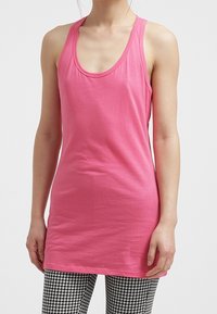 Różowy bezrękawnik z okrągłym dekoltem, wykonany z gładkiego materiału, w połączeniu z legginsami w czarno-białą kratę typu houndstooth.