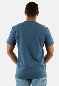 Camiseta de manga corta para hombre en azul, hecha de algodón suave. Presenta un cuello redondo y un corte relajado, con una textura suave y costuras mínimas.