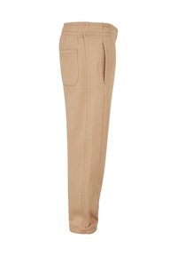 Beige tapered Jogginghosen mit elastischem Bund und Bündchen, ausgestattet mit einer Gesäßtasche und seitlichen Taschen.