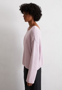Lichtroze gebreide trui met een brede halslijn, losse pasvorm en lange mouwen. De textuurstof heeft een ontspannen, casual ontwerp.