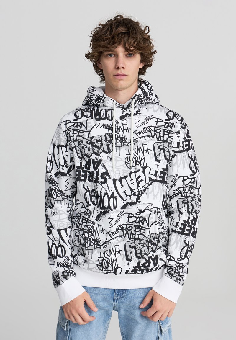 Felpa con cappuccio bianca con stampa in stile graffiti nera. Presenta una tasca a marsupio frontale e polsini a costine. Materiale in cotone.