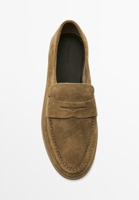 Braune Wildlederschlupfschuhe mit einem gestickten Design und kleinen Quasten-Details, vor einem schlichten weißen Hintergrund.