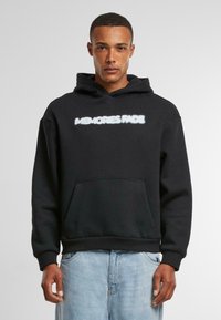 Zwarte hoodie met een voorzak en witte tekst "MEMORIES FADE" over de borst. Gemaakt van zachte stof, met een capuchon met trekkoord.