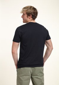 Svart kortärmad t-shirt gjord av ett mjukt, slätt tyg. Har en klassisk rund halsringning och en avslappnad passform.