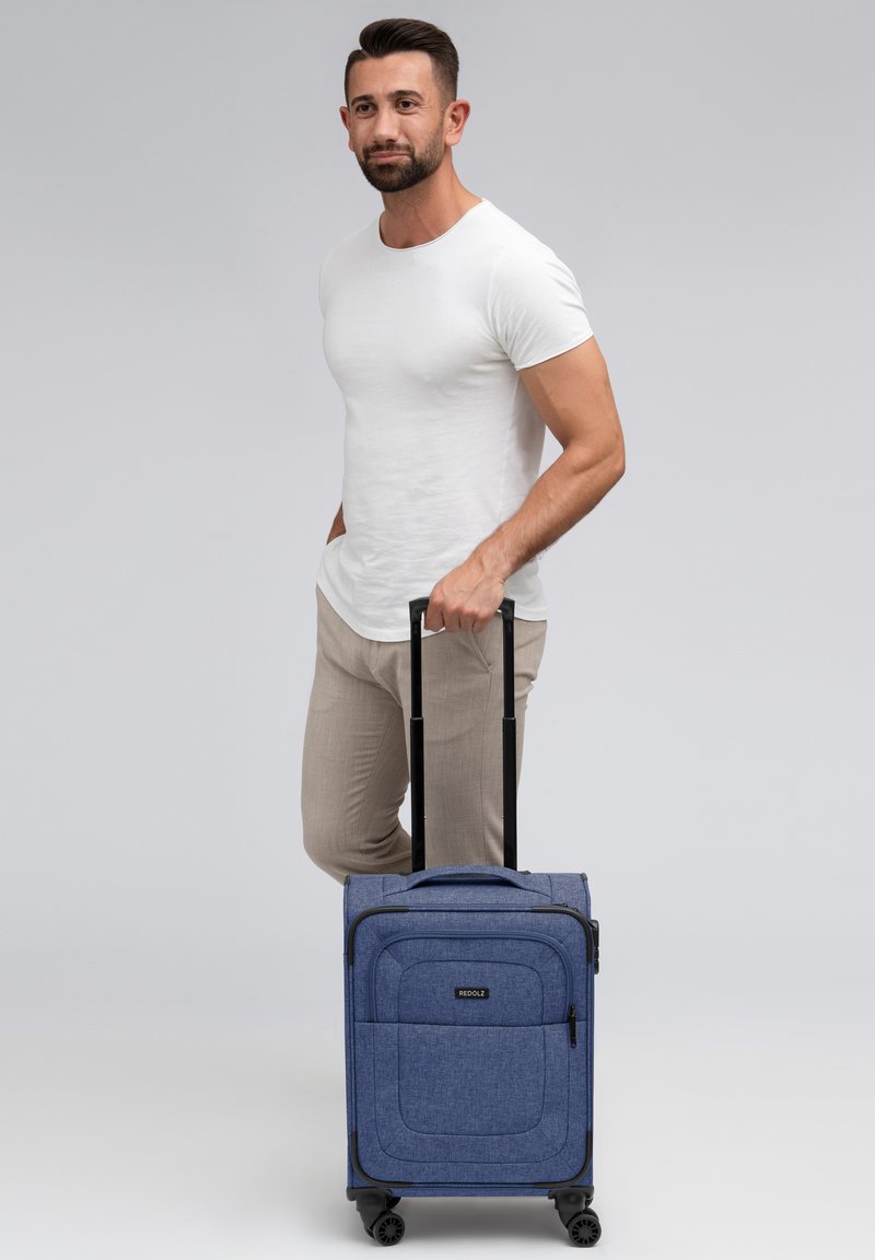 Valigia a mano in tessuto blu con manico rinforzato, ruote lisce e tasche con zip frontali; dimensioni adatte per il viaggio.