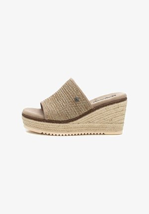 Sandalia de cuña con parte superior de tela beis trenzada, puntera abierta y suela texturizada estilo espadrille. Presenta un acento decorativo metálico.