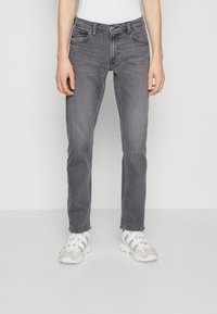 Grå denimjeans med rak passform, fem fickor och subtila blekningar. Matcher med vita sportskor.