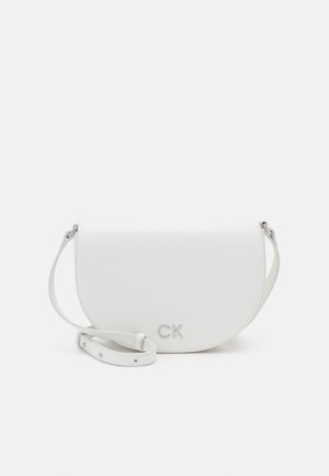 Weiße Halbmond-Umhängetasche mit verstellbarem Riemen und silbernem "CK"-Logo vorne vor einem einfarbigen hellen Hintergrund.