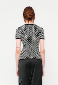 Zwart-wit gestreepte aangesloten top met korte mouwen en een ronde halslijn, voorzien van een geometrisch ontwerp en een effen zwarte zoom.