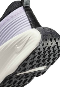 Black and white Nike shoe with a textured rubber sole, layered upper in light purple and black, featuring a raised Nike logo.