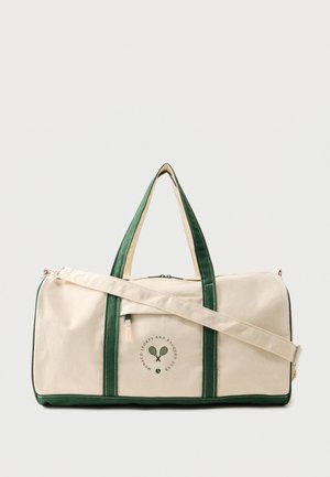 Prostokątna beżowa torba płócienna z zielonymi uchwytami i wykończeniem, przednią kieszenią na zamek, regulowanym paskiem na ramię oraz logo klubu sportowego z rakietami tenisowymi.