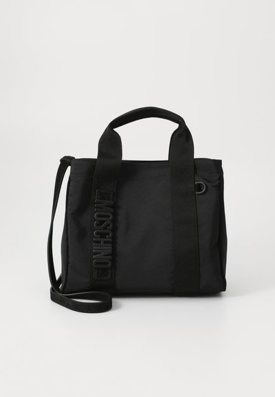 Black tote bag made of durable fabric. Features short handles, a detachable strap, and embossed logo detailing on the side.