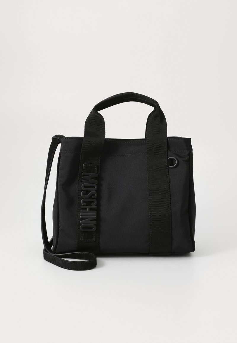 Sac fourre-tout noir en tissu durable. Il dispose de poignées courtes, d'une bandoulière amovible et d'un logo en relief sur le côté.