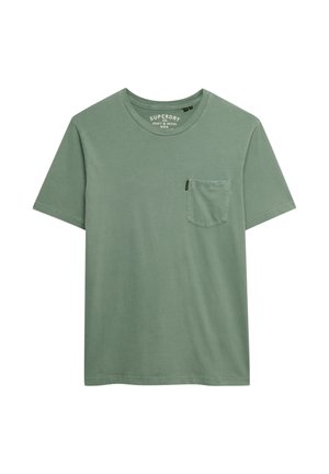 Camiseta verde de manga corta con cuello redondo, bolsillo en el pecho izquierdo delantero y pequeña etiqueta negra en el borde del bolsillo.