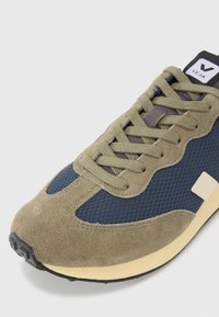 Navy mesh og oliven suede sneaker med beige såle. Har rund tå, snøredesign og en liten logoetikett på tungen.