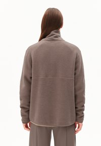 Giacca in fleece grigio-marrone con colletto alto, spalle cadute e una superficie testurizzata. Presenta un design pulito con cucitura posteriore.