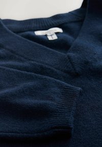 Marineblauer Wollpullover mit V-Ausschnitt und elastischen Bündchen. Weiche Textur und glatte Oberfläche, die die Qualität und Handwerkskunst des Kleidungsstücks betont.